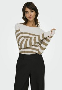 Pull rayé blanc et beige avec un décolleté bateau et des manches longues, associé à un pantalon noir à taille haute. Design simple, texture douce.