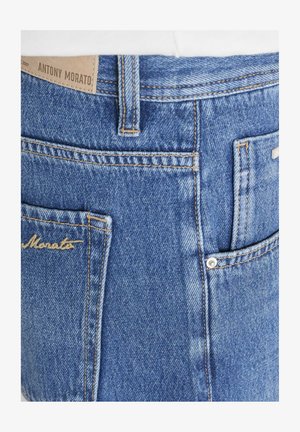 Blauwe denim jeans met achterzakken, zichtbare stiksels, riemlussen en een bruine leren merkembleem "Antony Morato" op de tailleband.
