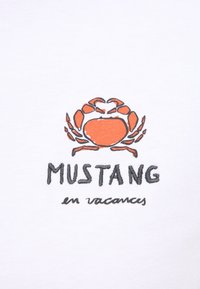 Baltas audinys su siuvinėtu dizainu, kuriame pavaizduotas oranžinis krabas virš juodu siuvinėjimu užrašytos frazės "MUSTANG en vacances".