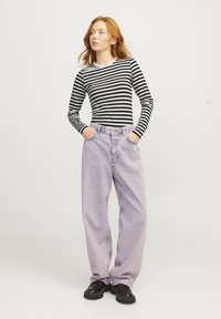 Striped langermet topp i svart og hvitt, kombinert med lyse lilla baggy jeans. Har høy midje og avslappet passform, med svarte sko.