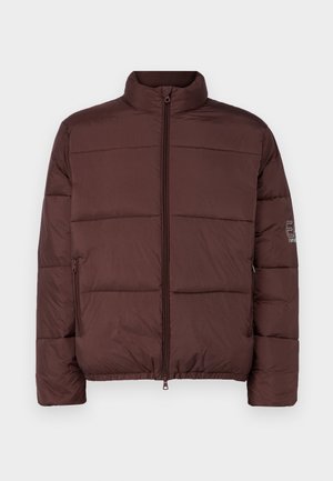 Barna, steppelt dzseki magas gallérral, elülső cipzárral és oldalsó zsebekkel. Tűzött panelek és minimális márkázás található az ujjon.