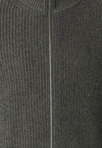 Vetoketjullinen neulepaita, valmistettu tummanharmaasta resorikankaasta, jossa on korkea kaulus ja hopeinen vetoketjusuljin keskellä.