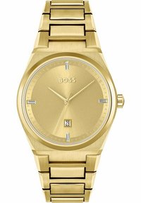Reloj de pulsera en tono dorado con una esfera redonda minimalista, índices horarios plateados y una pantalla de fecha a las 6 en punto, con una correa metálica a juego.