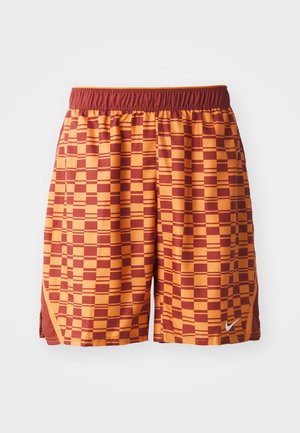 Pantalones cortos deportivos de cuadros naranja y marrón con cinturilla elástica y pequeño logo blanco de Nike en el dobladillo delantero.