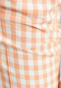 Orange och vit rutmönstrad tyg, texturerad väv, med en mjuk känsla, med ett mönster av växlande rutor.