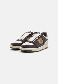 Sneakers in pelle con una combinazione di colori marrone e bianco, punta perforata e pannelli laterali testurizzati. Lacci spessi e suole in gomma completano il design.