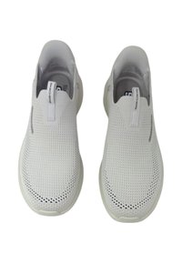 Sneakers bianchi senza lacci con tomaia in mesh traspirante, texture liscia, design minimale e un'etichetta a ciclo sul tallone.