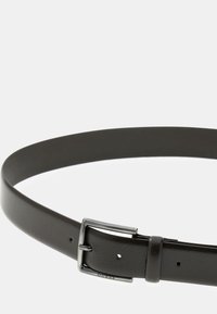Brun læderbælte med en glat overflade, udstyret med en sølvmetal spænde og en brandgravering på remmen, designet til en klassisk pasform.