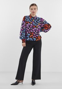 Lilleline must blouse, millel on värvid nagu lilla, punane ja sinine. Pilves varrukad ja kitsas mansett. Kombineeritud mustade laiade pükste jaol.
