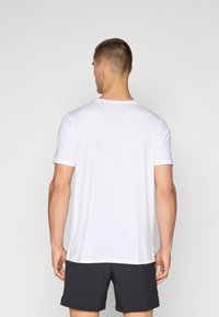 Weißes Kurzarm-Sportshirt mit Rundhalsausschnitt, aus einem glatten, leichten Stoff, kombiniert mit schwarzen Shorts.