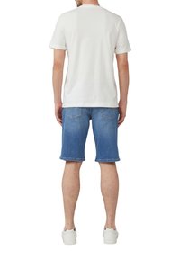 Witte katoenen T-shirt met korte mouwen, gecombineerd met lichtblauwe denim shorts, met een omgeslagen Zoom en twee achterzakken. Draag het met witte sneakers.