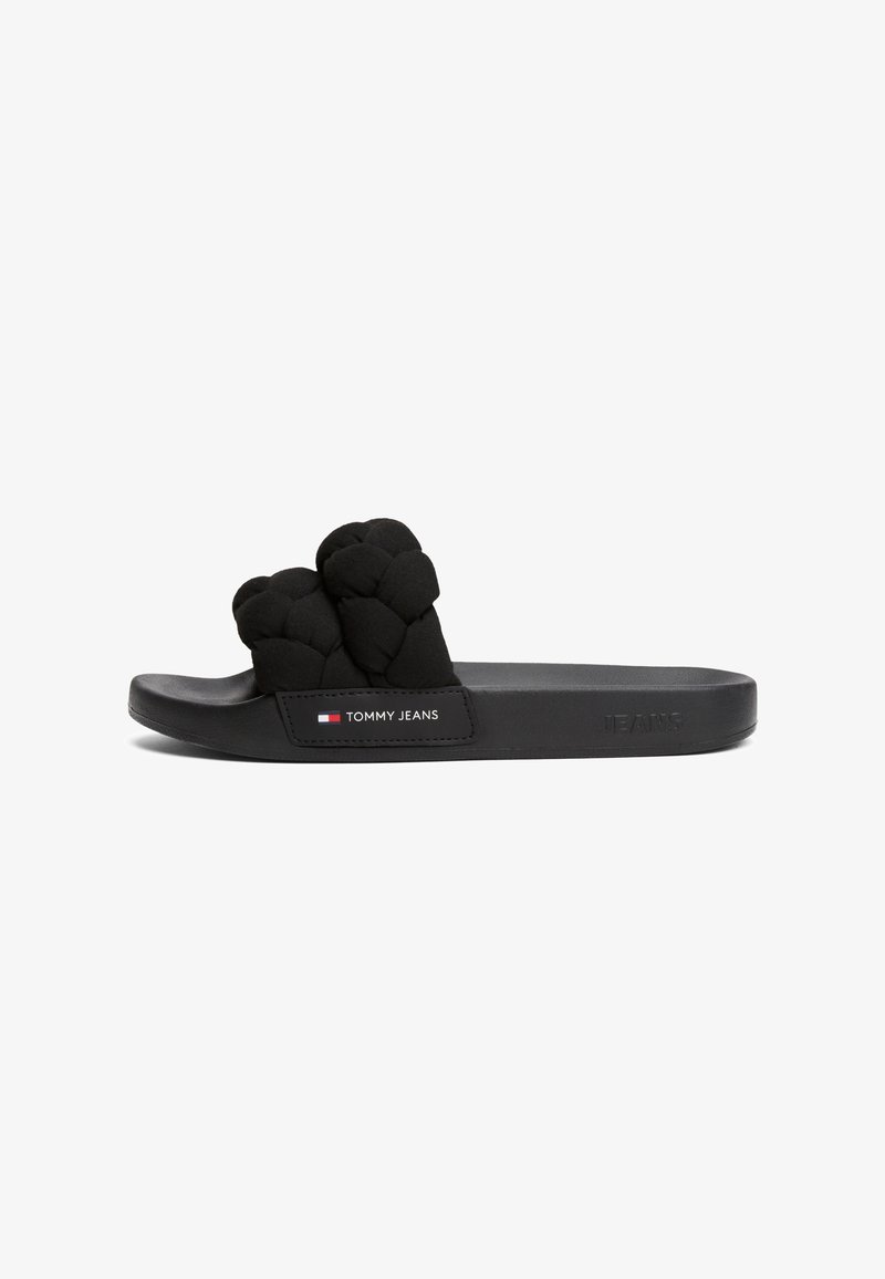 Sandale à glissière noire avec une bride tressée matelassée et une semelle en caoutchouc. Comprend une étiquette logo sur le côté et une partie supérieure texturée.