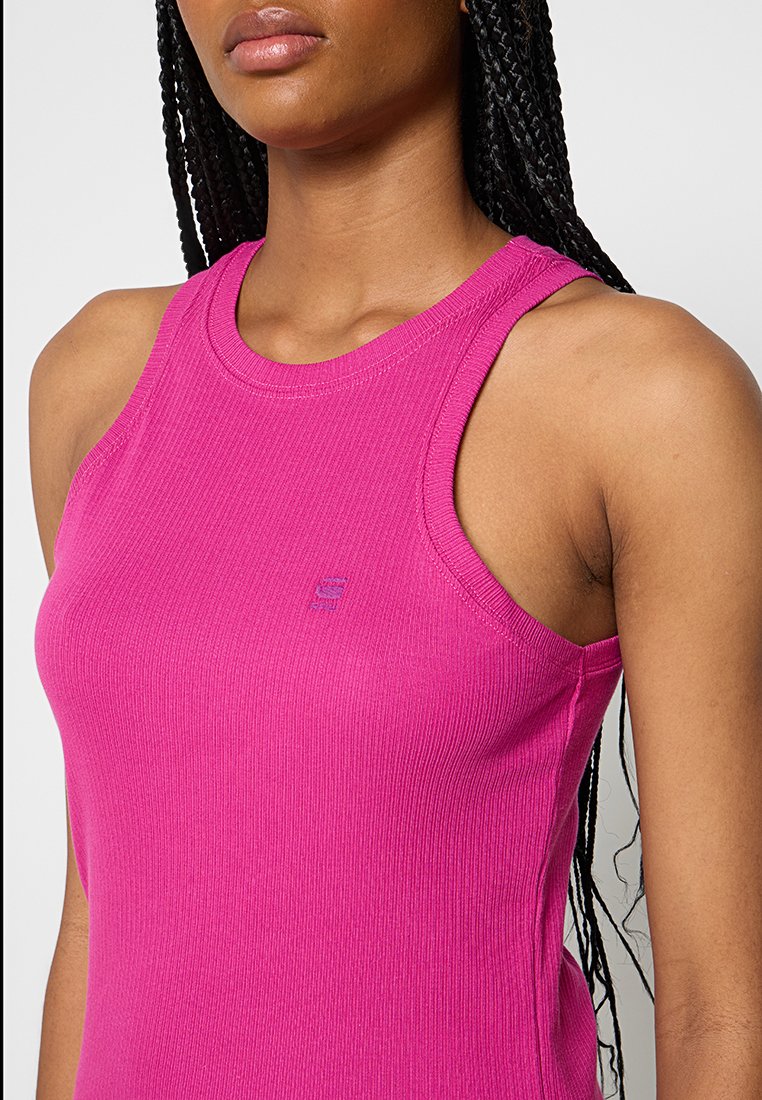 Top in magenta a coste aderente, con collo alto e ampie aperture per le braccia. Dettaglio del logo in una tonalità leggermente più scura.