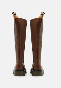 Brown leather knee-high boots with a smooth finish, vertical seams, and a textured rubber sole. Includes pull tabs for easy wear.