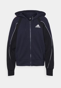 Sudadera con cremallera de color azul marino y capucha. Paneles en negro, detalles en blanco y un logotipo bordado en el pecho. Material suave con puños acanalados.