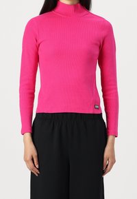 Úzký dlouhý rukáv rolák v živé růžové ribbené tkanině, s rovnými lemy a malou značkovou visačkou po straně.