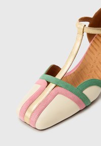 Έγχρωμο επίπεδο παπούτσι με τετράγωνη μύτη, κατασκευασμένο από κρεμ δέρμα μ ε ροζ και πράσινες σουέντ λεπτομέρειες και χρυσό λουράκι. Ομαλή υφή σε όλο το παπούτσι.