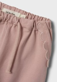 Lyserøde bomuldsshorts med elastisk talje, der viser et dekorativt bølget stikmønster på siden og en snorelukning.