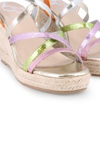 Sandalias de cuña con tiras metálicas iridiscentes en rosa, verde y plateado, con una plataforma envuelta en yute y una puntera suave y dorada.