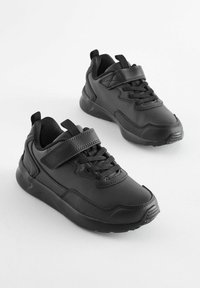 Baskets de sport noires en matériau synthétique avec lacets et une sangle Velcro. Bout arrondi et semelle rembourrée pour plus de confort.