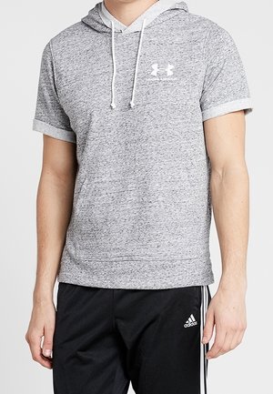 Mand iført en grå Under Armour kortærmet hættetrøje og sorte Adidas træningsbukser med hvide striber på siderne.