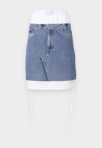 Farmernadrág szoknya kék alappal, fehér perforált derékrésszel és húzózsinórral. Elöl zsebekkel és egyenes szabással rendelkezik, nyers szegéllyel.