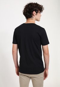 Black cotton t-shirt with short sleeves, a crew neckline, and a smooth texture. The design features a simple, unadorned back.
