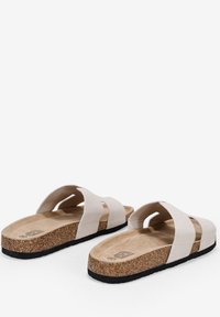 Sandalias de color beige claro con dos correas anchas, plantilla de corcho y suela de goma texturizada, que cuentan con un diseño de soporte para el arco para mayor comodidad.