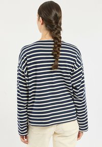 Navy and cream striped long-sleeve shirt with a round neckline and relaxed fit. Soft fabric, visible stitching, and drop shoulders.
