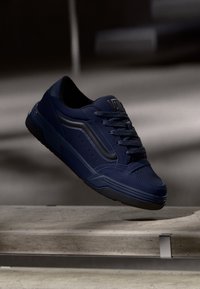 Granatowe sneakersy o gładkiej fakturze, z czarnymi akcentami, okrągłym czubkiem i sznurowanym zapięciem. Gumy podeszwa z wzorem bieżnika.