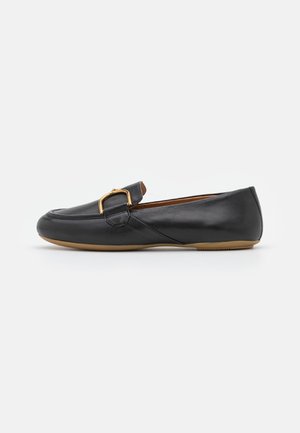 Chaussure plate en cuir noir à bout arrondi, ornée d'une boucle dorée et d'une semelle en caoutchouc beige. Texture lisse avec des coutures minimales.