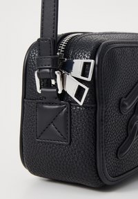 Sac en cuir noir texturé en bandoulière avec quincaillerie en argent, fermeture à double zip et une sangle plate dotée d'un accent rectangulaire.