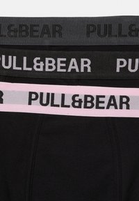 Tre paia di biancheria intima nera con fascia elastica in grigio, nero e rosa, ognuna con il nome del marchio PULL&BEAR.