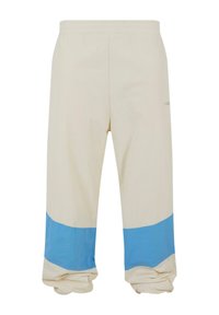 Pantaloni bej cu o bandă largă albastră aproape de tiv. Confecționați dintr-un material moale, cu o talie elastică și o croială lejeră.
