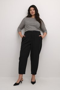 Haut rayé noir et blanc à manches 3/4 associé à un pantalon noir taille haute et des escarpins noirs à bout pointu. Tissu lisse et coupe ajustée.