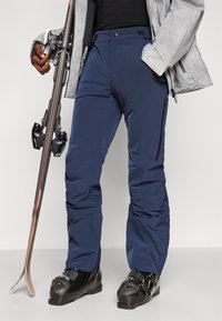 Pantaloni de schi bleumarin cu un design drept, realizați dintr-un material rezistent la apă, având fermoare laterale și genunchi întăriți pentru durabilitate.