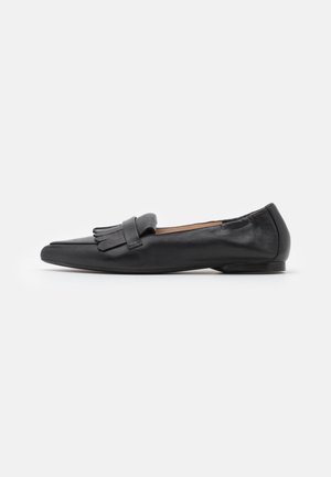 Sort læder flad loafer med spids tå og dekorativ frynset gudebind på toppen, vist i sideprofil.