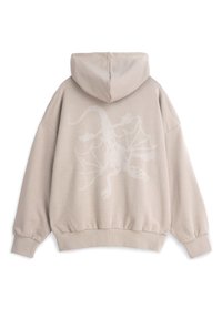 Beżowy, oversize'owy hoodie z kapturem na sznurki. Na plecach znajduje się biały, haftowany wzór jaszczurki. Miękki, teksturowany materiał.