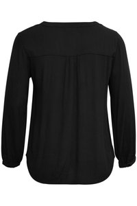Blouse noire à manches longues avec une texture lisse, un col rond et un détail discret de pliure au dos. L'ourlet inférieur est légèrement incurvé.