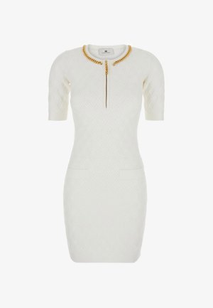 Robe blanche à manches courtes avec un tissu texturé, dotée d'un accent en chaîne dorée autour de l'encolure et de deux poches avant. Fermeture éclair sur le devant.