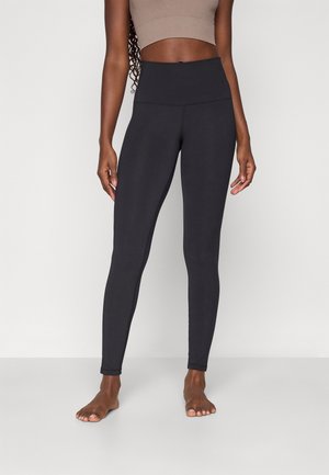 Svarte leggings laget av elastisk stoff har høy linning og en tettsittende design, perfekt for komfort og bevegelsesfrihet.