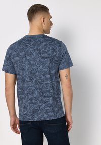 Modré tričko s kulatým výstřihem s texturovaným vzorem v tmavších odstínech. Krátké rukávy, normální střih, vyrobené z měkké bavlněné směsi.