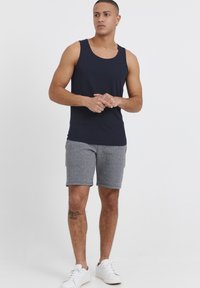 Marineblaues ärmelloses Tanktop, kombiniert mit grauen strukturierten Shorts und weißen Sneakers. Verfügt über einen runden Ausschnitt und einen lässigen Schnitt.