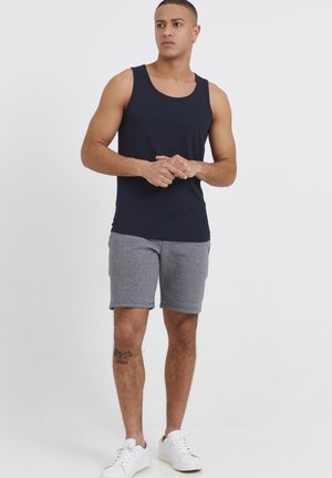 Marineblaues ärmelloses Tanktop, kombiniert mit grauen strukturierten Shorts und weißen Sneakers. Verfügt über einen runden Ausschnitt und einen lässigen Schnitt.