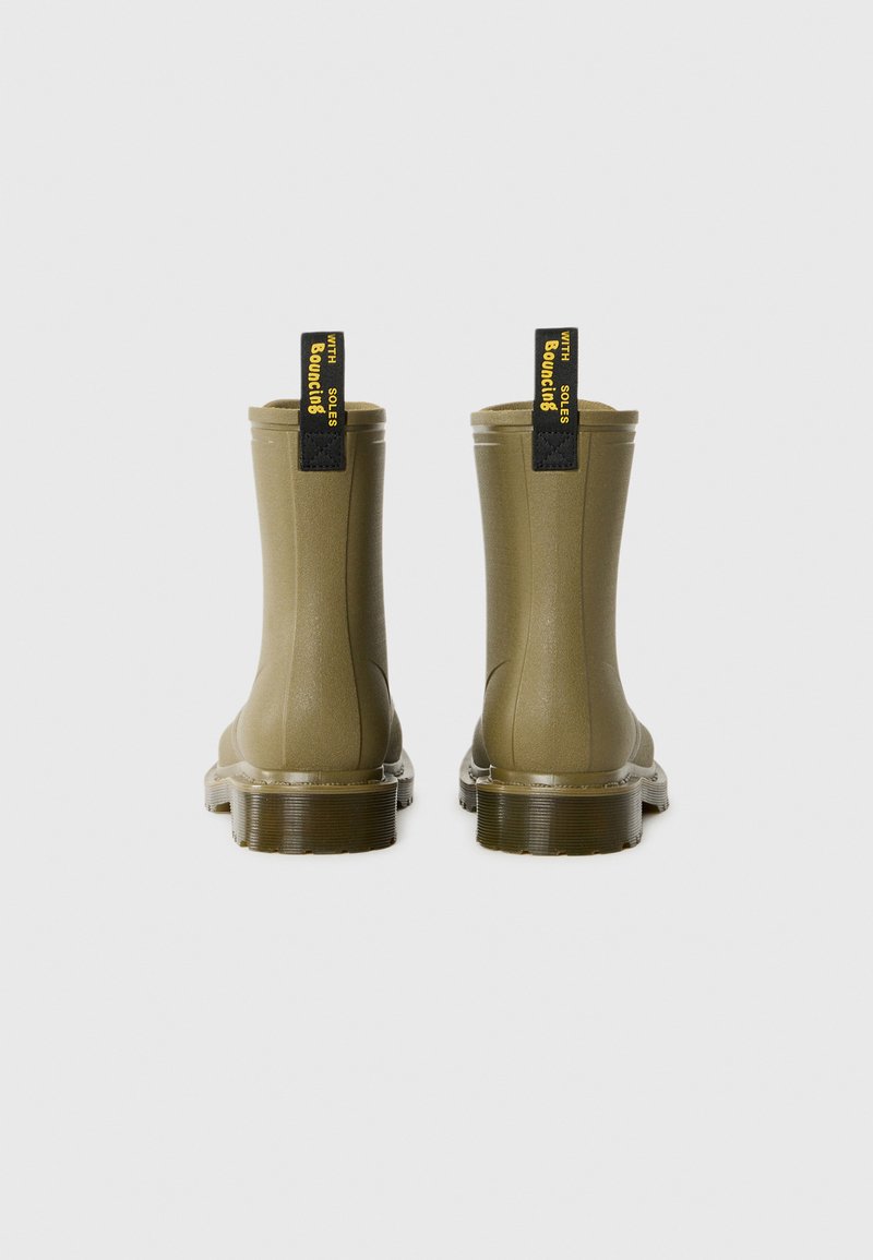 Olive green waterproof boots with a smooth finish, short height, and black pull tabs labeled "with Bouncing Soles." Textured rubber soles.