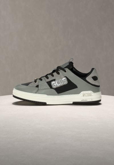 Γκρι και μαύρο χαμηλό παπούτσι με λευκή σόλα, μαύρα κορδόνια και λογότυπο "GCDS" στο πλάι και στη σόλα, εμφανίζονται πάνω σε ουδέτερη επιφάνεια.