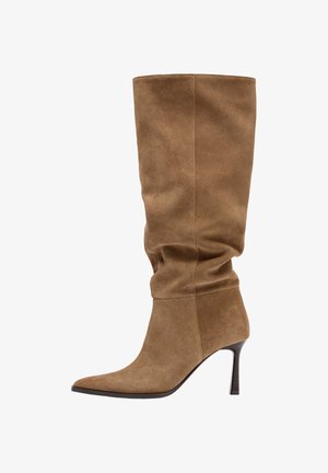 Brun ruskinds knæhøj støvle med spids snude og slank mellemhøj hæl, med et let afslappet skaftdesign.