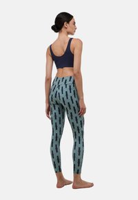 Brassière de sport bleu marine et leggings à motifs turquoise et crème, présentant des designs géométriques. Les leggings sont ajustés avec une taille haute.