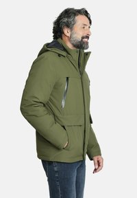 Chaqueta aislante verde olivo con capucha, bolsillos frontales con cremallera y un bolsillo en la parte delantera con solapa, que presenta una textura suave y un diseño casual.