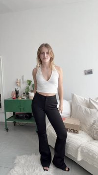 Top cropped branco canelado com decote em V combinado com calças pretas largas. O conjunto apresenta uma textura suave e um estilo minimalista.